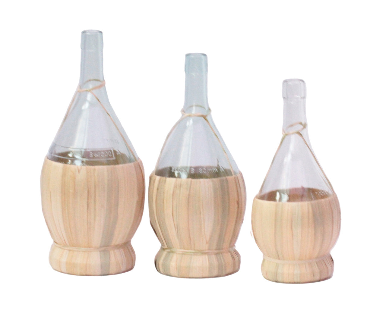 Three glass Chianti bottles with wooven bases on a white background
